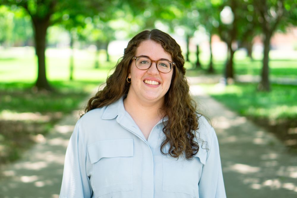 Woman smiling at camera with trees behind her