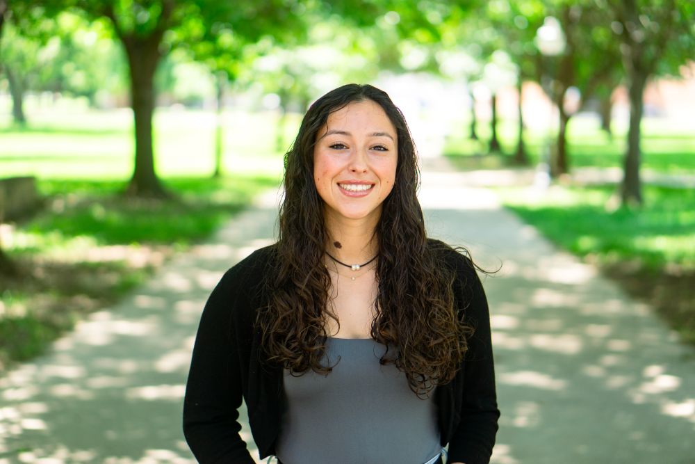 Woman smiling at camera with trees behind her
