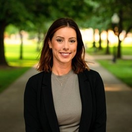 Woman smiling at camera with trees behind her