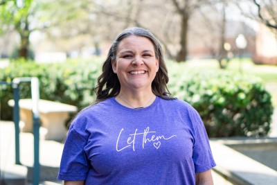 Woman smiling at camera with trees behind her