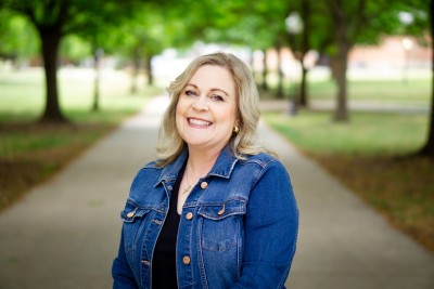 Woman smiling at camera with trees behind her
