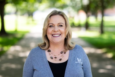 Woman smiling at camera with trees behind her