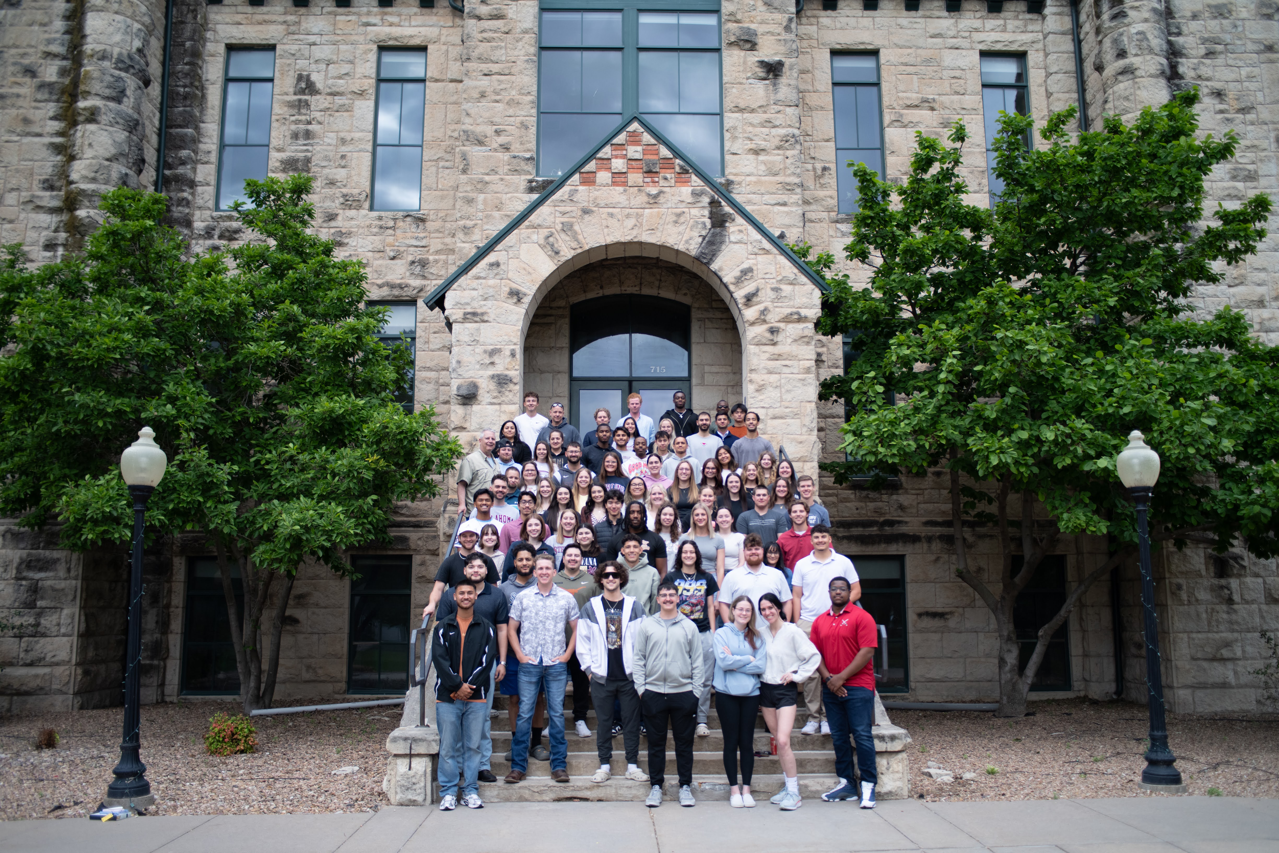 Students Outside Standing in front of a building smiling at the camera