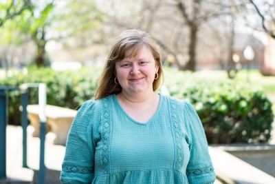 Woman smiling at camera with trees behind her