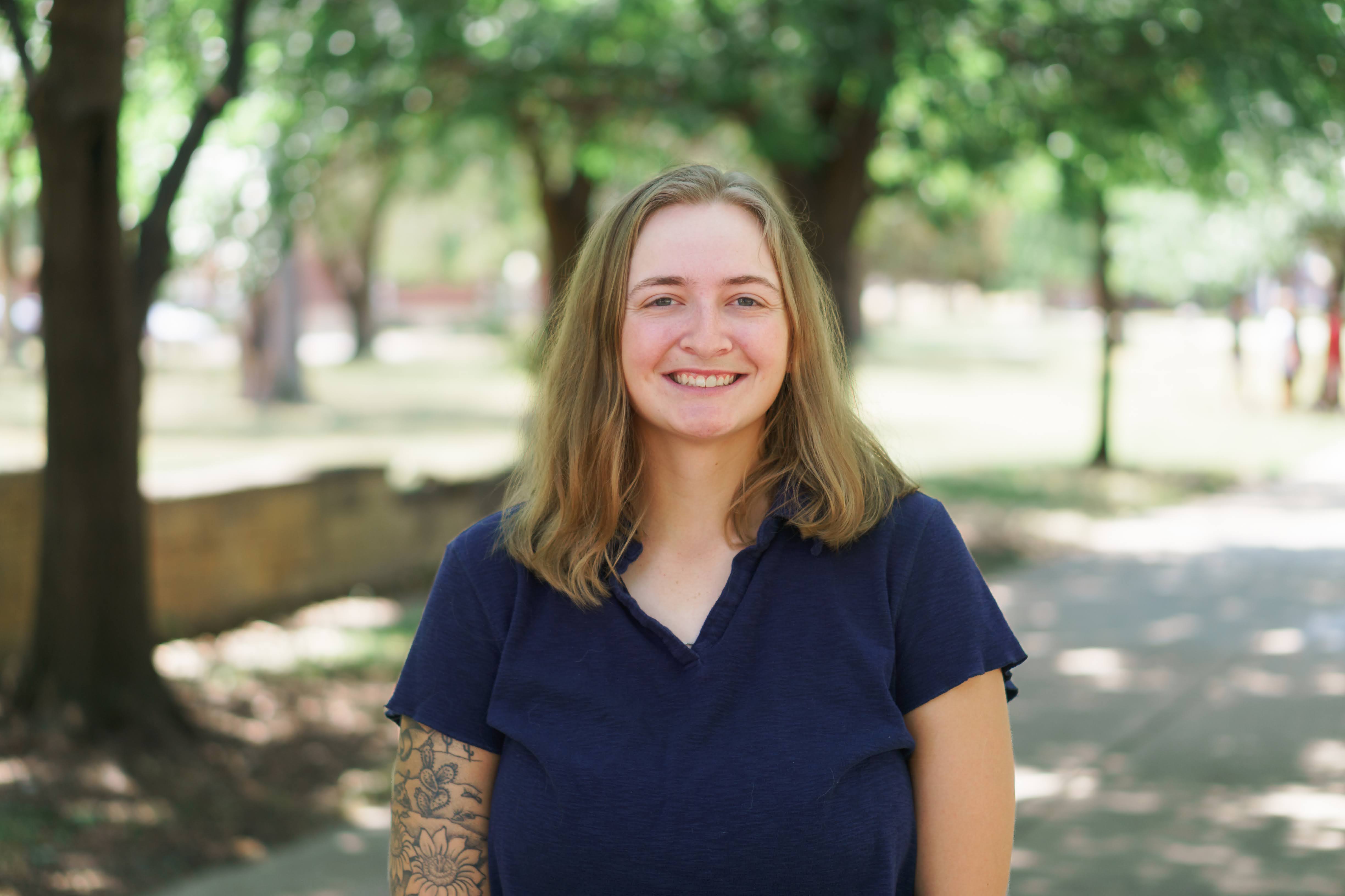 Woman smiling at camera with trees behind her
