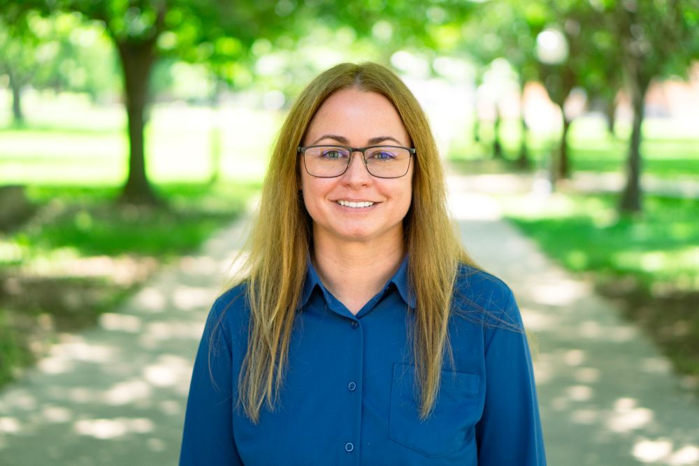 Woman smiling at camera with trees behind her