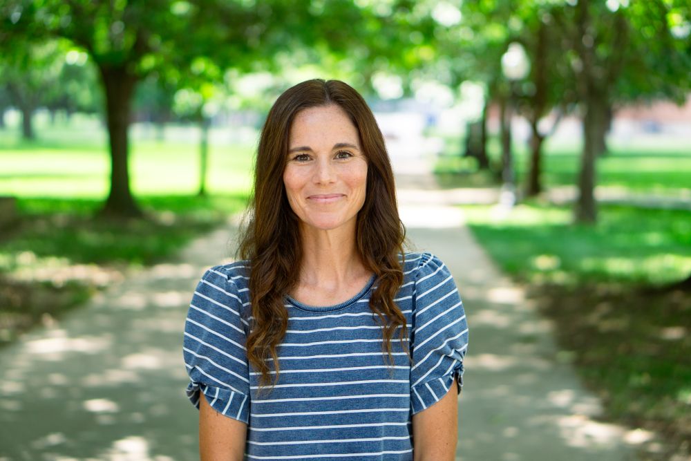 Woman smiling at camera with trees behind her