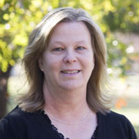 Woman smiling at camera with trees behind her