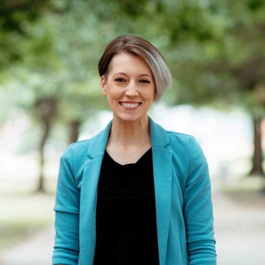 Woman smiling at camera with trees behind her