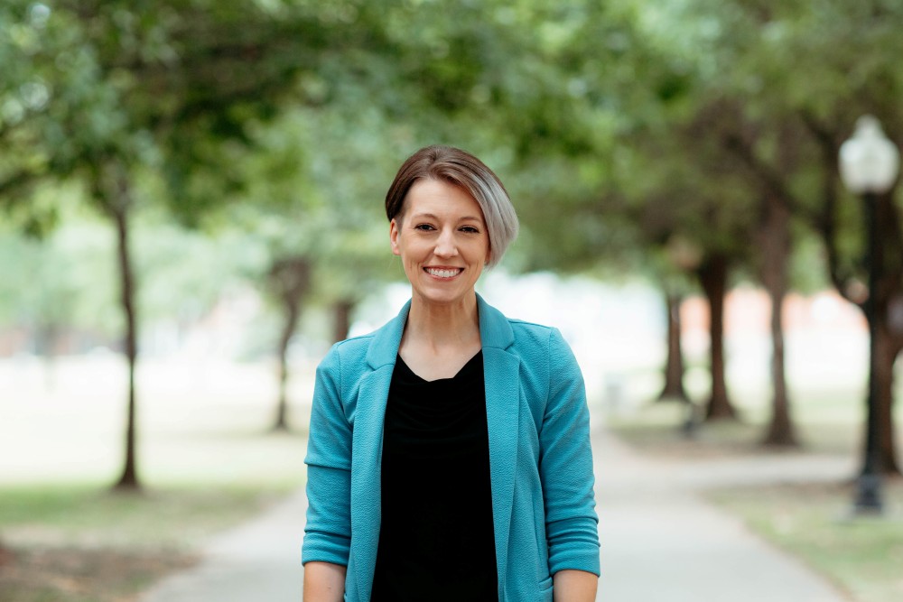 Woman smiling at camera with trees behind her