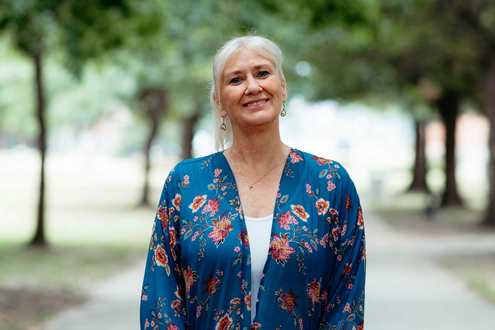Woman smiling at camera with trees behind her