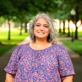 Woman smiling at camera with trees behind her