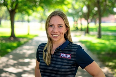 Woman smiling at camera with trees behind her