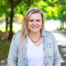 Woman smiling at camera with trees behind her
