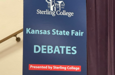 Blue sign that says Kansas State Fair Debates presented by Sterling College Blue sign that says Kansas State Fair Debates presented by Sterling College