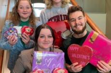 Four college student debate team members holding valentines decorations on a staircase
