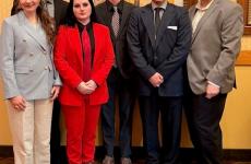 6 people standing dressed nicely and smiling at the camera