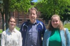 three people standing in the sunlight and posing for the camera