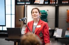 Woman wearing academic blazer smiling in front of crowd