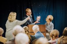 Woman is presented with a glass award at a podium