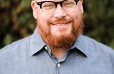 Man dressed nicely wearing glasses smiling at the camera