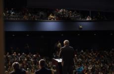 Auditorium of people with speaker facing the crowd from the stage