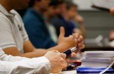 Close up shot of people lined up to talk to someone else on the other side of a table