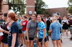 Two girls stand in the middle of a crowd of people, smiling at the camera Two girls stand in the middle of a crowd of people, smiling at the camera