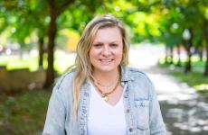 Woman smiling at camera with trees behind her