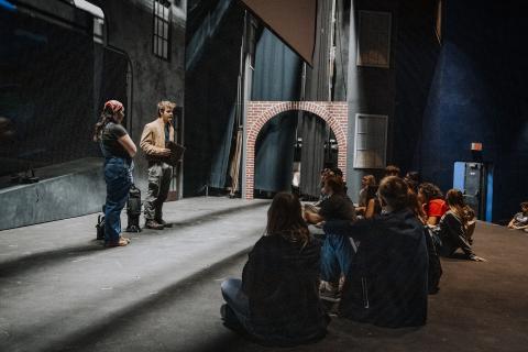 Students listening to teachers in theatre class on stage