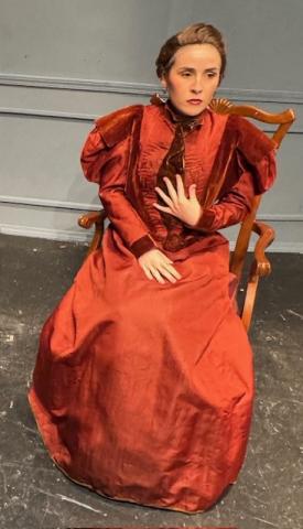 Woman sitting in a chair with a 19th century dress on