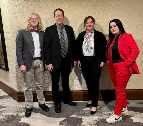 three students and a coach dressed nicely pose for photo