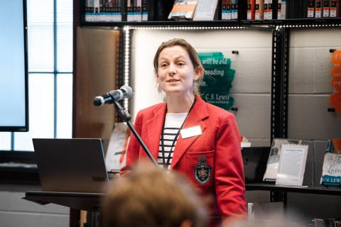 Woman wearing academic blazer smiling in front of crowd