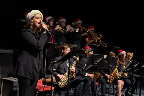 Girl singing on stage with musicians playing instruments behind