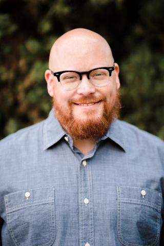 Man dressed nicely wearing glasses smiling at the camera