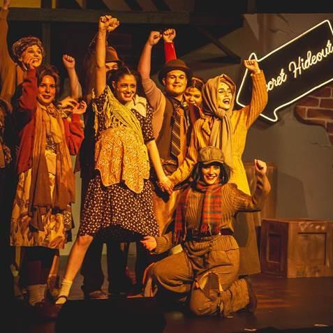 theatre students posing for the finale of a song with their hands in the air