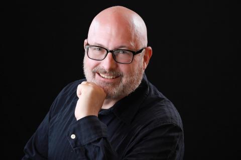 Man dressed nicely wearing glasses smiling at the camera