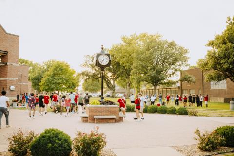 students outside playing games with a clock tower in the middle students outside playing games with a clock tower in the middle