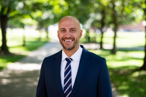 Man wearing a suit standing on the sidewalk and smiling at the camera