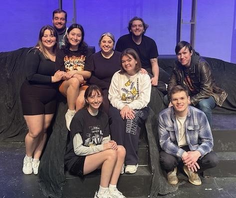 Group of students sitting on stage smiling at the camera