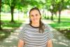 Woman smiling at camera with trees behind her