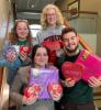 Four college student debate team members holding valentines decorations on a staircase