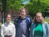three people standing in the sunlight and posing for the camera