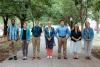 Seven people dressed nicely and standing on a sidewalk with trees behind them