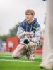 Man kneeling on field holding a camera